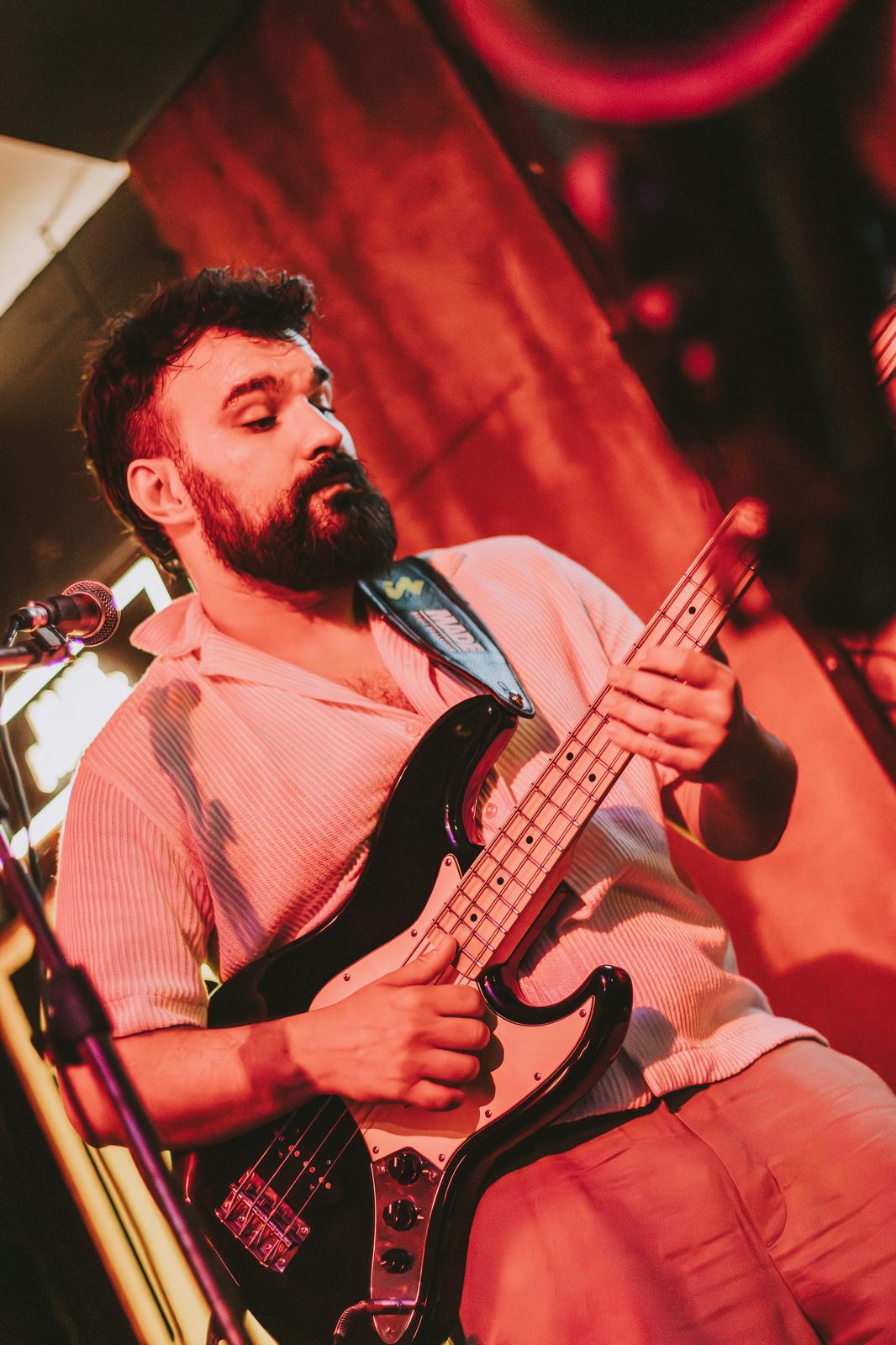 Lugue Henriques playing bass in a warm-lit bar, locked into the groove.