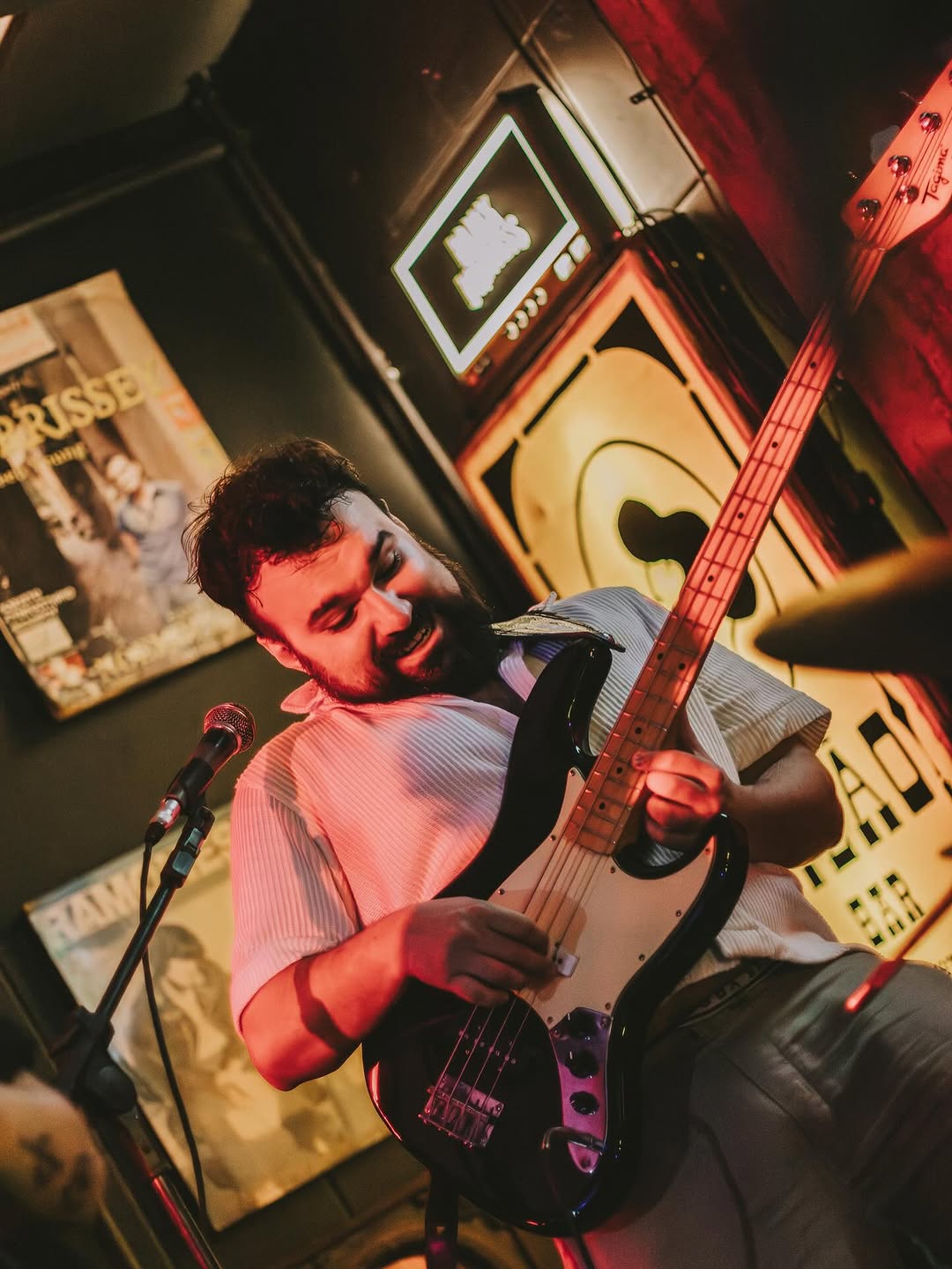 Lugue smiling while playing bass in a warm-lit bar.